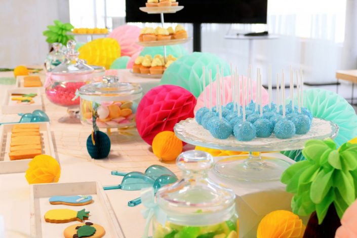 Bar à pâtisseries par Studio Candy pour L'Oréal - cake pops bleus, bonbons soucoupes, sablés décorés ananas, tongs, tortue, cupcakes