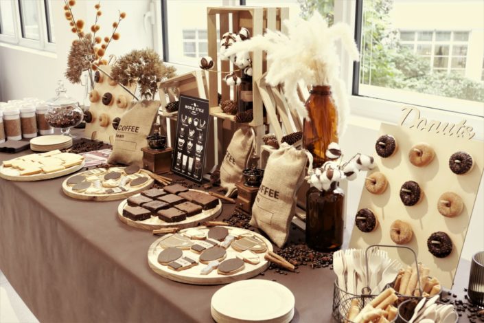 goûter thème café avec décoration, sacs de jute, grains de café, cannelle, vases fleurs de coton, financiers amande, brownie, donuts chocolat, sablés décorés