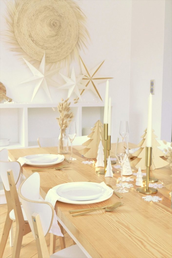 Table de Noël ambiance Laponie avec assiettes en céramique blanche, serviettes en lin blanc, flocons de neige, sapins en bois, bougeoirs dorés, fleurs séchées, couverts dorés mat