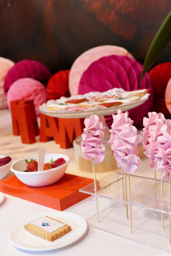 Table gourmande avec meringue rose, chamallows au chocolat, petits sablés culotte, goutte et bols de fruits rouges. Décoration rouge et rose - Studio Candy