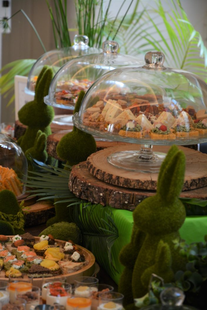 Table thème nature pour Au Féminin par Studio Candy - cloches en verre, mini sandwiches, lapins en mousse, rondins de bois et petits outils de jardin