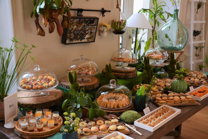 Table thème nature pour Au Féminin par Studio Candy - cloches en verre, mini sandwiches, lapins en mousse, rondins de bois, bonbonne géante et petits outils de jardin