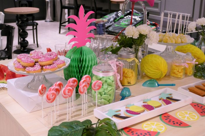 Table tropicale pour Adagio par Studio Candy - donuts roses à la fraise, sucettes, sablés décorés, bonbons et cake pops jaunes