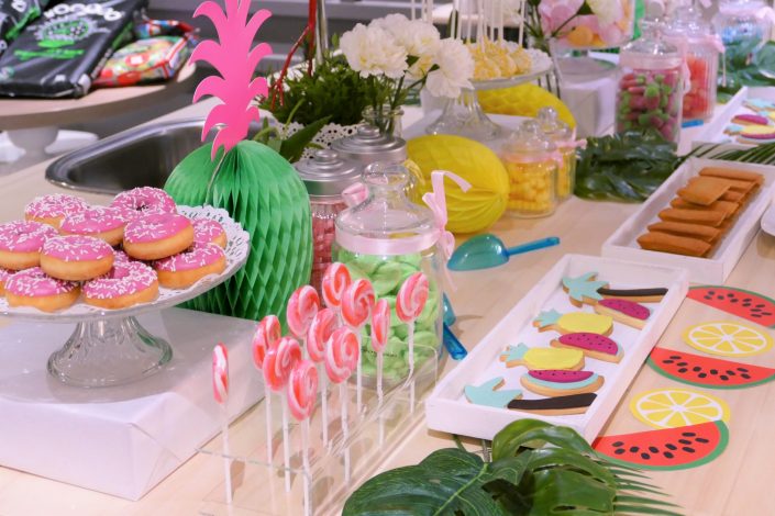 Table tropicale pour Adagio par Studio Candy - donuts roses, sucettes, sablés décorés, ananas, pastèque, palmier et bonbons