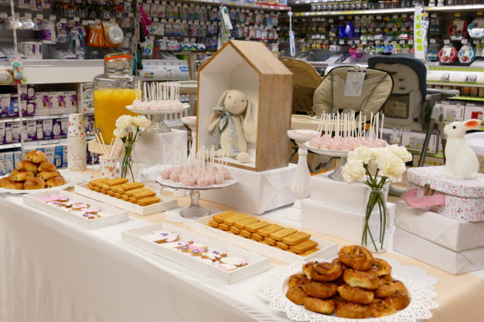 Sweet table thème bébé pour le magasin Toys'R Us de la Défense. Scénographie par Studio Candy. Cake pops roses, financiers, jus d'orange, viennoiseries, sablés décorés poussette, chausson, bavoir, body... et décoration thème Baby Shower