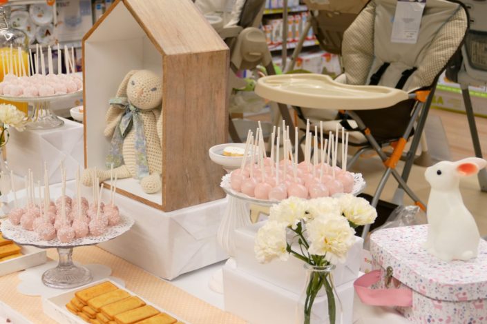 Sweet table thème bébé pour le magasin Toys'R Us de la Défense. Scénographie par Studio Candy. Cake pops roses, financiers, jus d'orange, viennoiseries, sablés décorés poussette, chausson, bavoir, body... et décoration thème Baby Shower