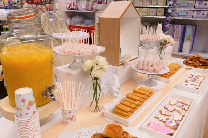 Sweet table thème bébé pour le magasin Toys'R Us de la Défense. Scénographie par Studio Candy. Cake pops roses, financiers, jus d'orange, viennoiseries, sablés décorés poussette, chausson, bavoir, body... et décoration thème Baby Shower