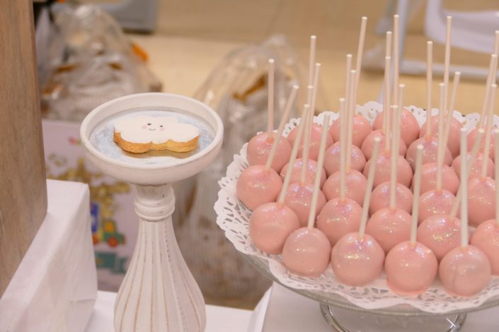 Sweet table thème bébé pour le magasin Toys'R Us de la Défense. Scénographie par Studio Candy. Cake pops roses, financiers, jus d'orange, viennoiseries, sablés décorés poussette, chausson, bavoir, body... et décoration thème Baby Shower