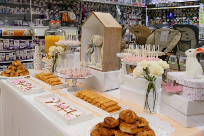 Sweet table thème bébé pour le magasin Toys'R Us de la Défense. Scénographie par Studio Candy. Cake pops roses, financiers, jus d'orange, viennoiseries, sablés décorés poussette, chausson, bavoir, body... et décoration thème Baby Shower