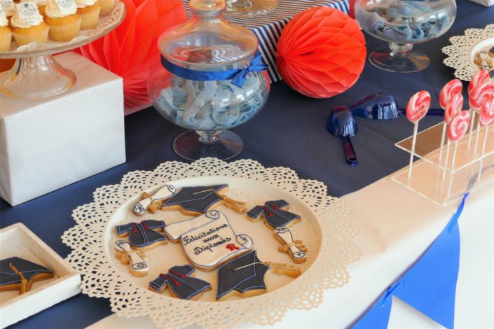 Fête des diplômés chez Babilou par Studio Candy - Sweet table, candy bar bleu, blanc et corail - Sablés décorés diplômes, toge, bonbons, sucettes, cupcakes avec logo, décoration