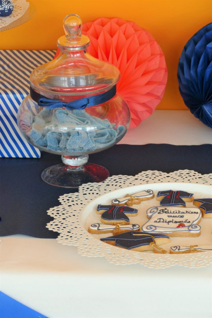 Fête des diplômés chez Babilou par Studio Candy - Sweet table, candy bar bleu, blanc et corail - Sablés décorés diplômes, toge, bonbons, sucettes, cupcakes avec logo, décoration