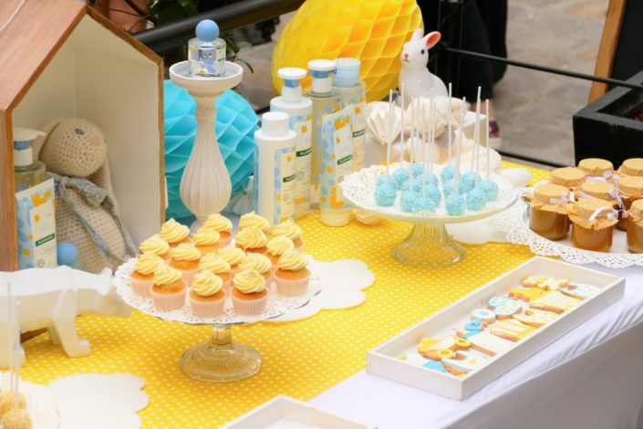 Sweet table / table goûter décorée par Studio Candy pour le lancement de la gamme bébé Klorane chez Au Féminin - sablés décorés, cake pops, petits pots de bébés, décoration jaune et bleue