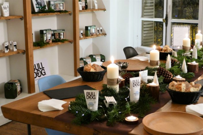 Scénographie, décoration de Noël pour la marque Bulldog par Studio Candy - sapin, table branche de sapin et pomme de pin, cheminée décorée