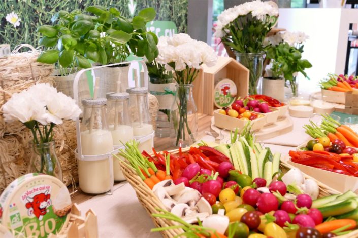 scénographie nature pour le lancement de Vache qui rit Bio - fleurs, basilic, bouteilles de lait, bar à pains, crudités, bois