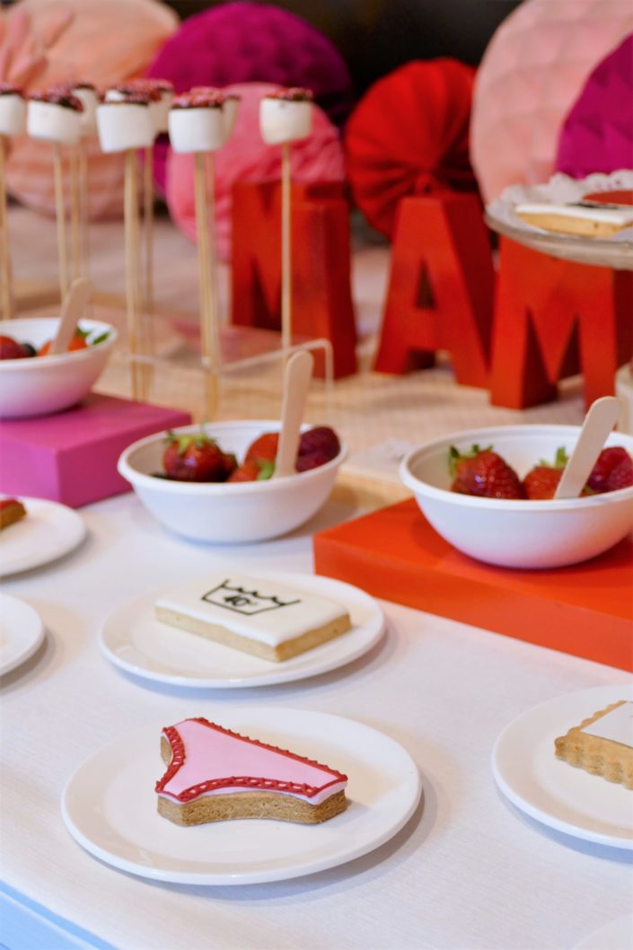 Table gourmande avec meringue rose, chamallows au chocolat, petits sablés culotte, goutte et bols de fruits rouges. Décoration rouge et rose - Studio Candy