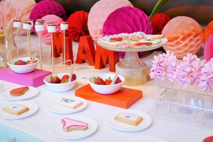 Table gourmande avec meringue rose, chamallows au chocolat, petits sablés culotte, goutte et bols de fruits rouges. Décoration rouge et rose - Studio Candy