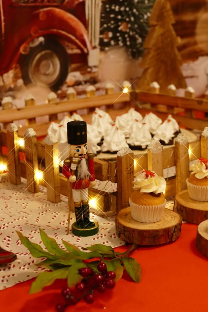 Goûter de Noël traditionnel avec petits sablés, cakepops rouges pailletés, chamallows bonhommes de neige, sapins meringue, petits oursons guimauve. Décoration en rouge, or, vert sapin avec des sucres d'orges, des bonbons, des sapins en bois