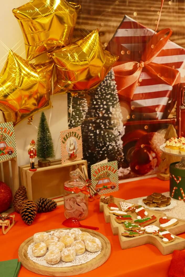 Goûter de Noël traditionnel avec petits sablés, cakepops rouges pailletés, chamallows bonhommes de neige, sapins meringue, petits oursons guimauve. Décoration en rouge, or, vert sapin avec des sucres d'orges, des bonbons, des sapins en bois