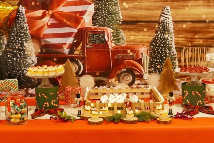 Goûter de Noël traditionnel avec petits sablés, cakepops rouges pailletés, chamallows bonhommes de neige, sapins meringue, petits oursons guimauve. Décoration en rouge, or, vert sapin avec des sucres d'orges, des bonbons, des sapins en bois