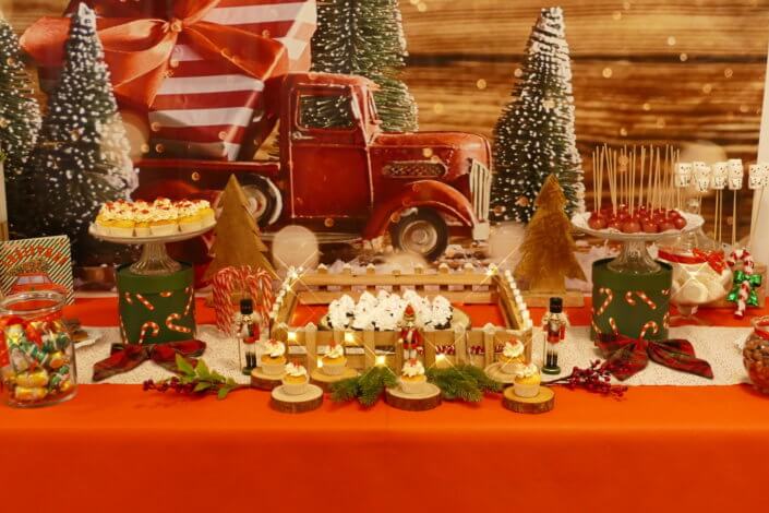 Goûter de Noël traditionnel avec petits sablés, cakepops rouges pailletés, chamallows bonhommes de neige, sapins meringue, petits oursons guimauve. Décoration en rouge, or, vert sapin avec des sucres d'orges, des bonbons, des sapins en bois