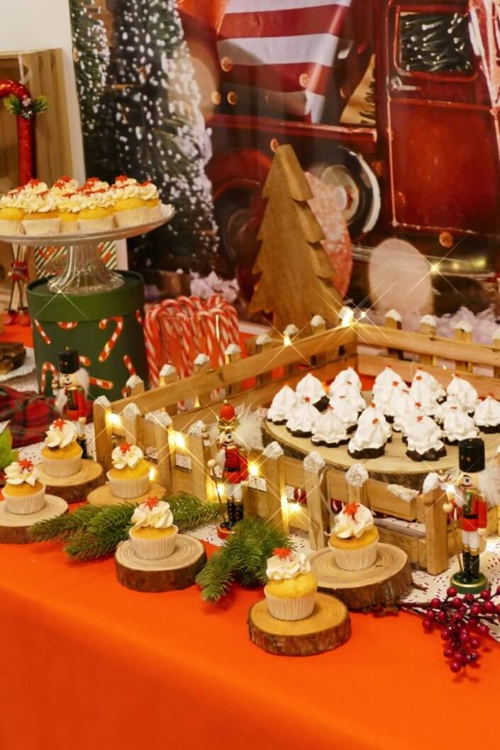 Goûter de Noël traditionnel avec petits sablés, cakepops rouges pailletés, chamallows bonhommes de neige, sapins meringue, petits oursons guimauve. Décoration en rouge, or, vert sapin avec des sucres d'orges, des bonbons, des sapins en bois