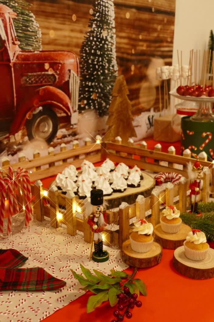 Goûter de Noël traditionnel avec petits sablés, cakepops rouges pailletés, chamallows bonhommes de neige, sapins meringue, petits oursons guimauve. Décoration en rouge, or, vert sapin avec des sucres d'orges, des bonbons, des sapins en bois