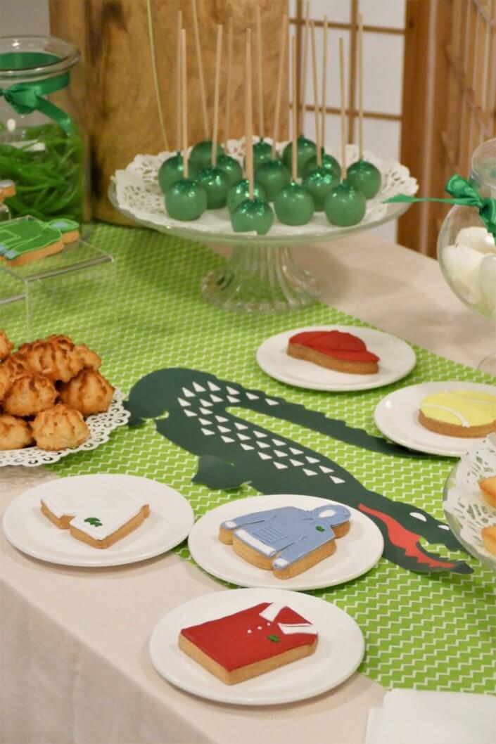 Goûter pour Lacoste avec sablés décorés short, polo, hoodies, casquette, balle de tennis. Cakepops verts, candy bar, financiers, boules coco et décoration crocodile en vert et blanc