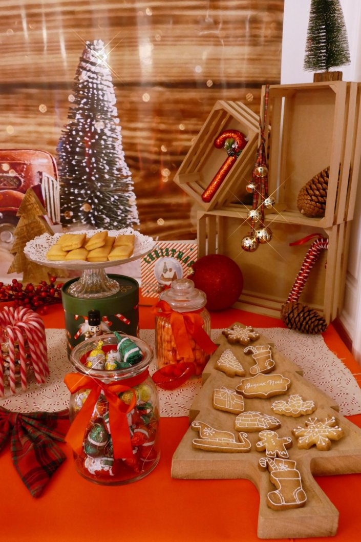 Goûter de Noël traditionnel avec sablés décorés, cake aux fruits, rochers coco, candy bar avec oursons guimauve, fraises tagada et décoration avec sapins, casse noisette, nœuds en tartan, sucres d'orge