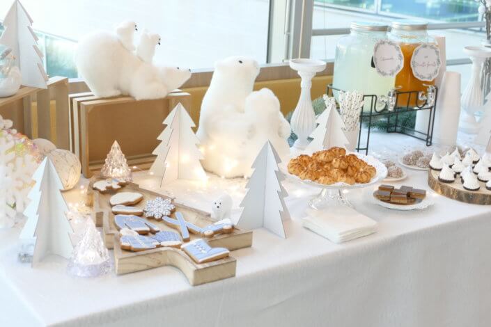 Goûter de Noël Polaire avec une décoration hiver enneigé en blanc : sapins pailletés, ours, pingouin, igloo. Fontaines à boissons, sapins meringue, financiers, sablés décorés de Noël