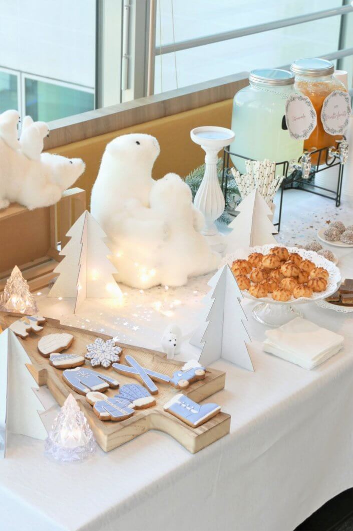 Goûter de Noël Polaire avec une décoration hiver enneigé en blanc : sapins pailletés, ours, pingouin, igloo. Fontaines à boissons, sapins meringue, financiers, sablés décorés de Noël