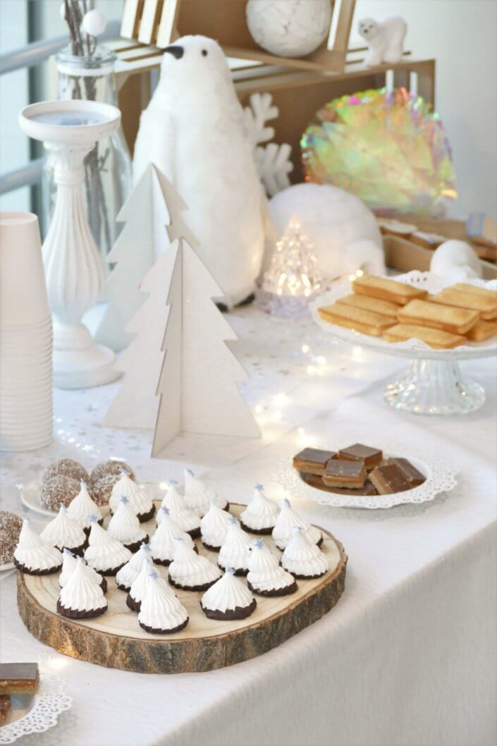 Goûter de Noël Polaire avec une décoration hiver enneigé en blanc : sapins pailletés, ours, pingouin, igloo. Fontaines à boissons, sapins meringue, financiers, sablés décorés de Noël