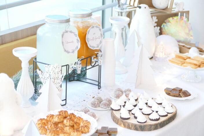 Goûter de Noël Polaire avec une décoration hiver enneigé en blanc : sapins pailletés, ours, pingouin, igloo. Fontaines à boissons, sapins meringue, financiers, sablés décorés de Noël