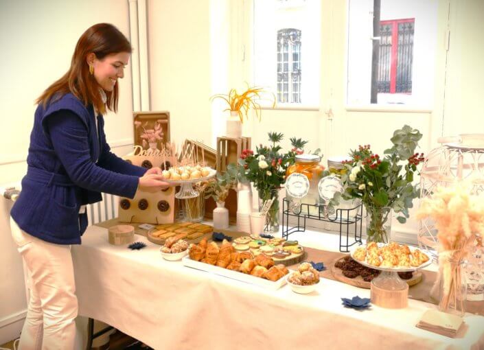 Réalisation d'une table gourmande décorée avec cake pops, sablés décorés, roses des sables, financiers, fleurs fraîches, fontaines à boissons d'eaux infusées, chemin de table en toile de jute, lanternes en bois.