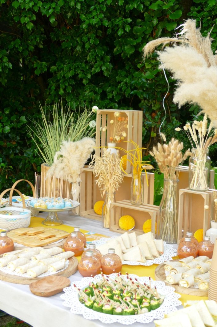 Pool party Uriage avec buffet décoré sur mesure de fleurs séchées, lanternes en bois, patisseries et sablés décorés en forme de crème solaire, cakepops, financiers, gâteaux