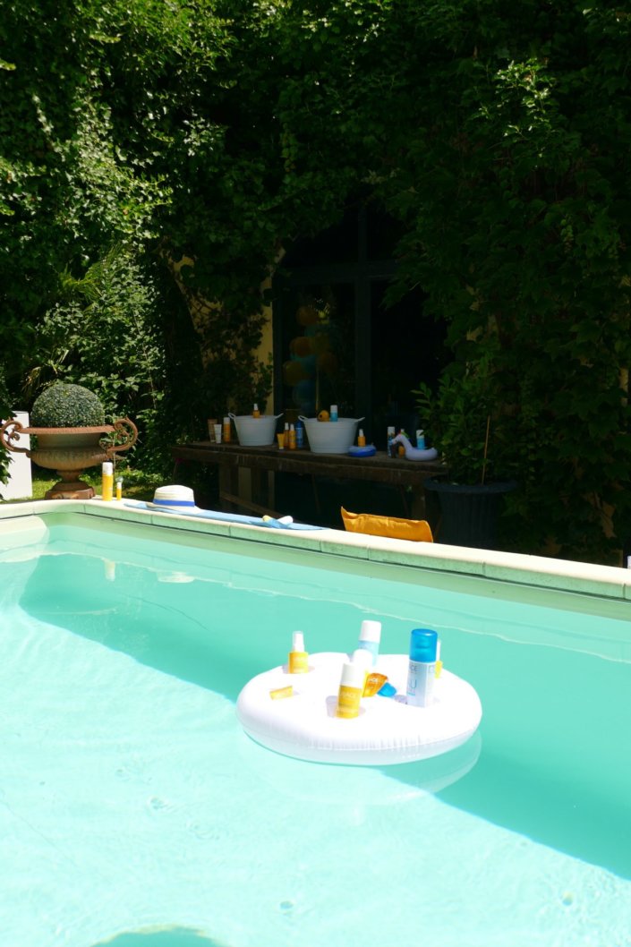 Pool party Uriage avec buffet décoré sur mesure de fleurs séchées, lanternes en bois, patisseries et sablés décorés en forme de crème solaire, cakepops, financiers, gâteaux