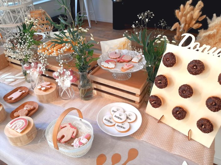 Goûter thème bébé dans les tons beige et rose poudré pour la nouvelle collection BabyBjorn : sablés décorés hochet, poussette, biberon, body, donuts, cakepops, fudge, financier et décoration