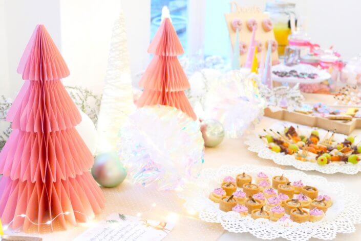 Table de Noël pour la soirée influence des parfums Adopt' - Décoration en blanc et rose, sablés décorés de Noël sur mesure, financiers, brownie, fontaines à boissons et pièces salées roses sur mesure.