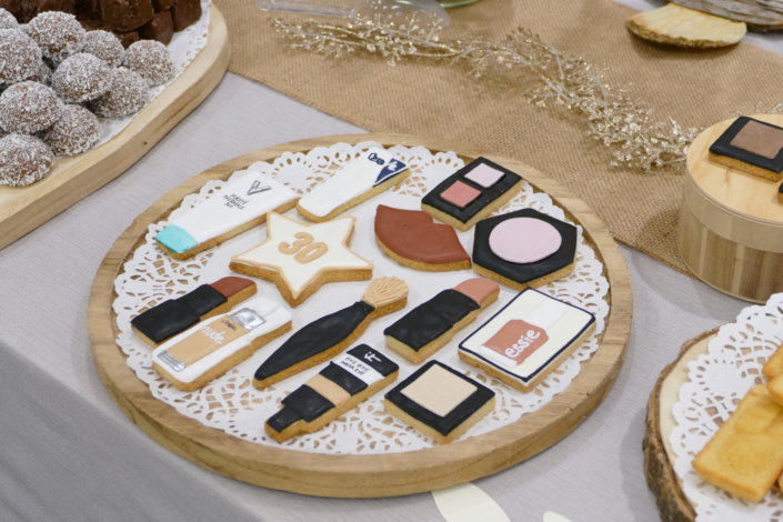 remise des médailles chez L'Oréal avec une table de goûter sur mesure réalisée par Studio Candy tout en or, bois et beige avec des sablés décorés Kerastase, Vichy, vernis Essie, crème CeraVe