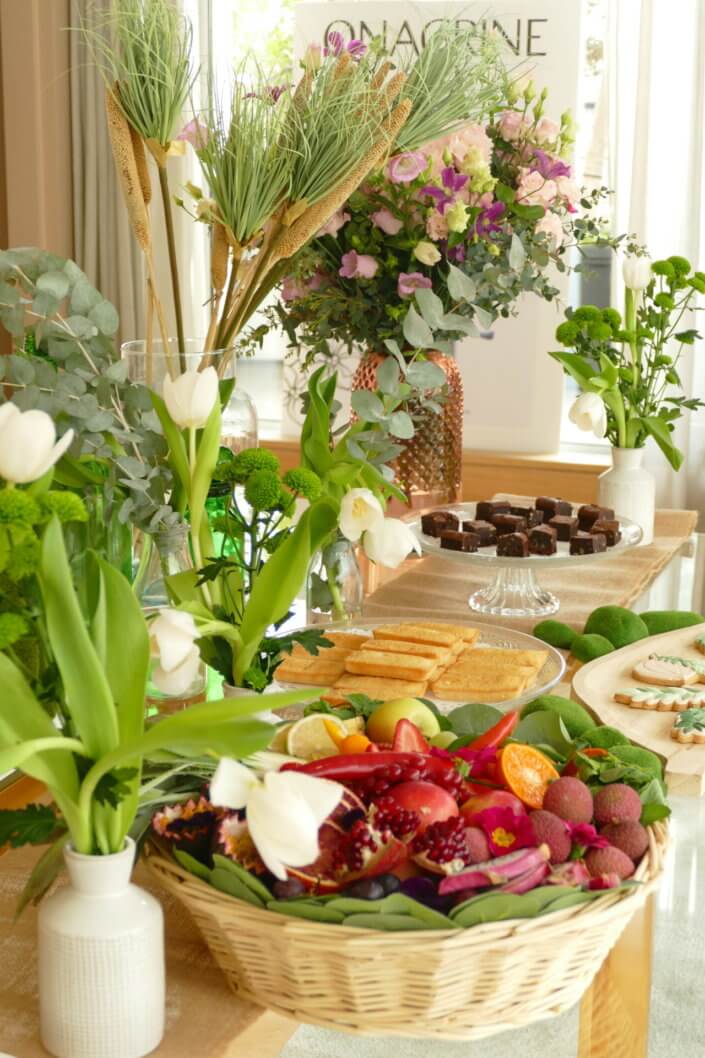 Journée presse Noreva avec une table nature et printanière par Studio Candy avec sablés décorés feuillage, financier, brownie aux noix, granola, verrines, brochettes de fruits et crudités, grazing cônes et décoration green nature de tulipe, eucalyptus et fleurs fraîches