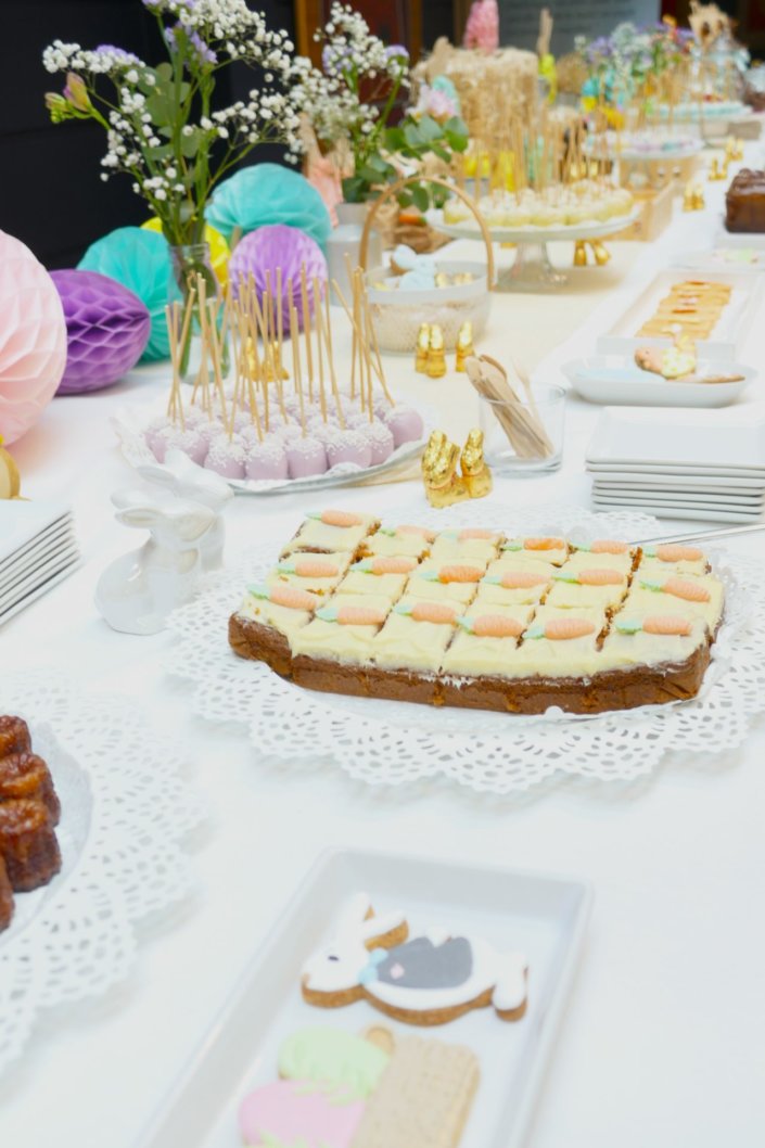 Goûter de Pâques avec oeufs en chocolat, carrot cake, cake marbré vanille chocolat, cakepops, fruits, financiers, roses des sables, sablés décorés, décoration bottes de foin et fleurs fraîches par STUDIO CANDY