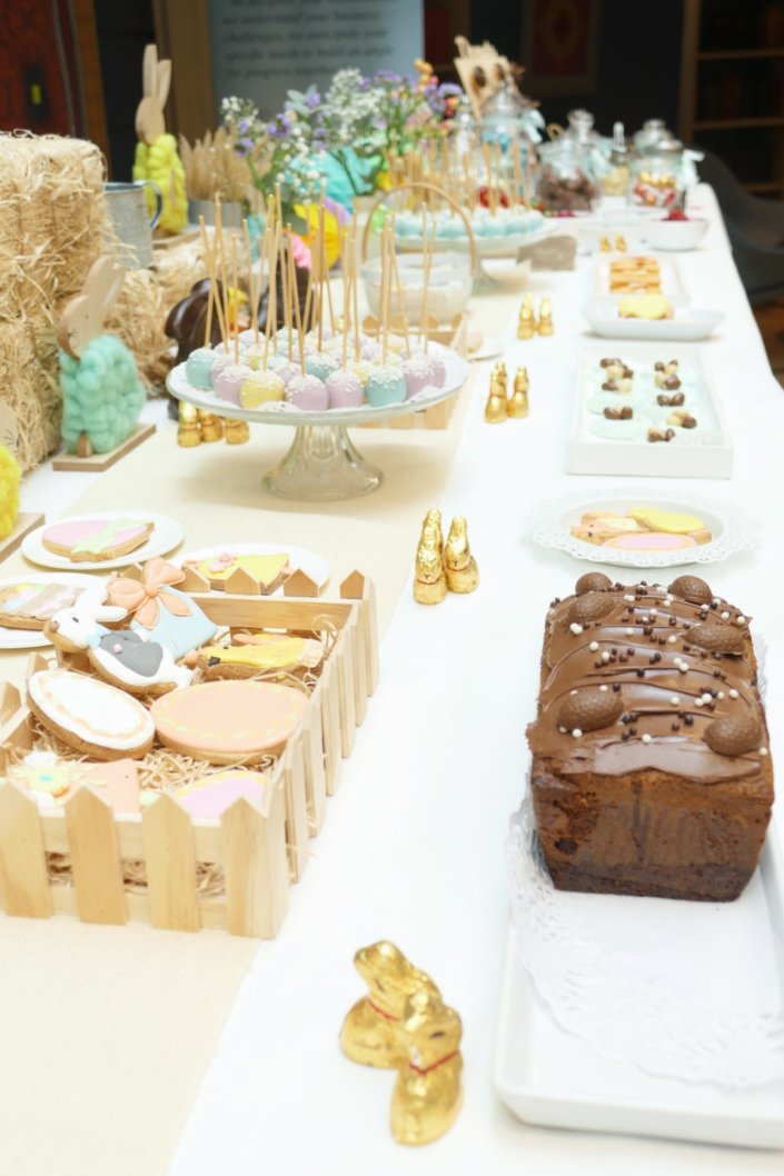 Goûter de Pâques avec oeufs en chocolat, carrot cake, cake marbré vanille chocolat, cakepops, fruits, financiers, roses des sables, sablés décorés, décoration bottes de foin et fleurs fraîches par STUDIO CANDY