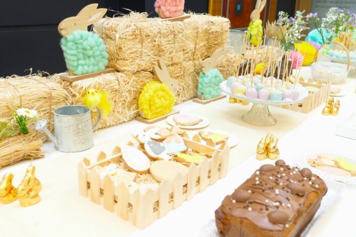 Goûter de Pâques avec oeufs en chocolat, carrot cake, cake marbré vanille chocolat, cakepops, fruits, financiers, roses des sables, sablés décorés, décoration bottes de foin et fleurs fraîches par STUDIO CANDY