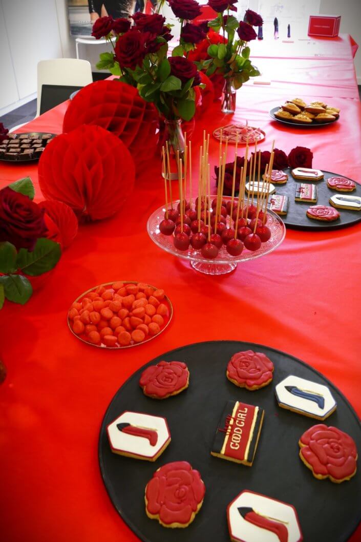 Lancement du parfum Very Good Girl de Carolina Herrera avec Studio Candy : table sur mesure avec des sablés décorés, cakepops rouges pailletés, madeleines, brownie, nappage rouge, bouquets de roses rouges