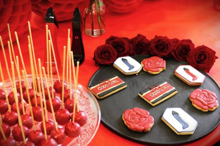 Lancement du parfum Very Good Girl de Carolina Herrera avec Studio Candy : table sur mesure avec des sablés décorés, cakepops rouges pailletés, madeleines, brownie, nappage rouge, bouquets de roses rouges