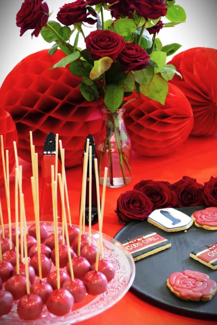 Lancement du parfum Very Good Girl de Carolina Herrera avec Studio Candy : table sur mesure avec des sablés décorés, cakepops rouges pailletés, madeleines, brownie, nappage rouge, bouquets de roses rouges