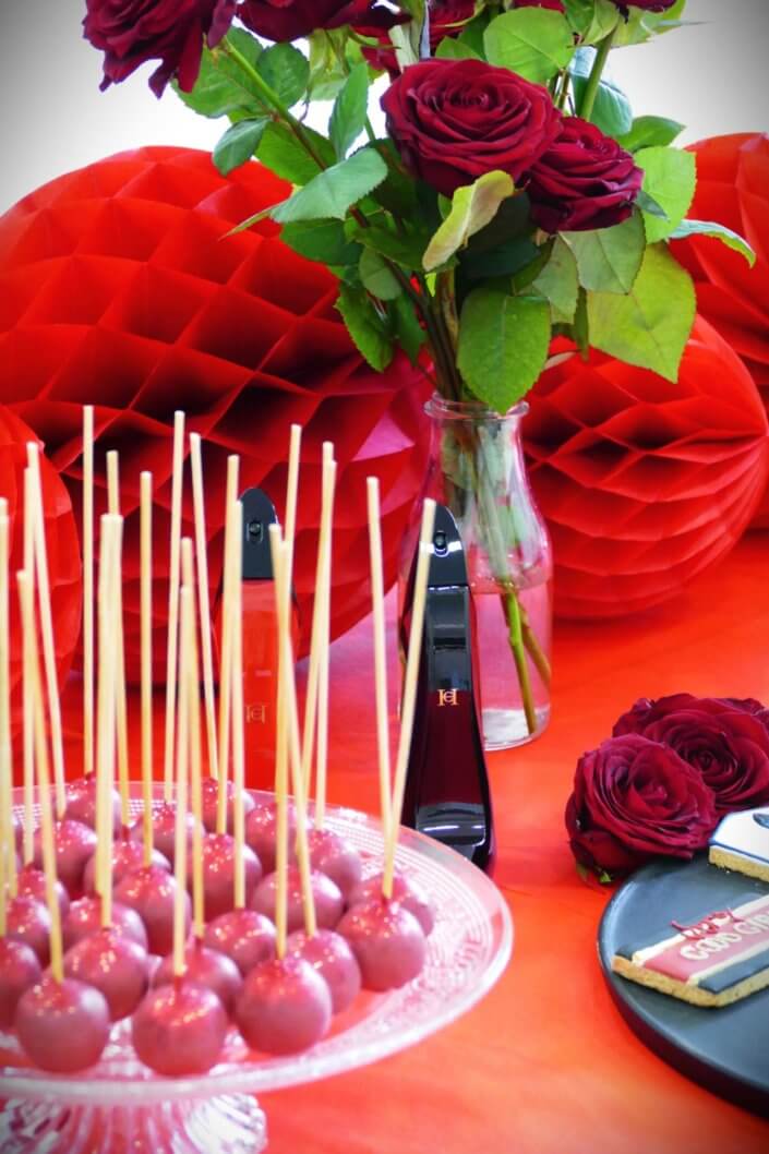 Lancement du parfum Very Good Girl de Carolina Herrera avec Studio Candy : table sur mesure avec des sablés décorés, cakepops rouges pailletés, madeleines, brownie, nappage rouge, bouquets de roses rouges