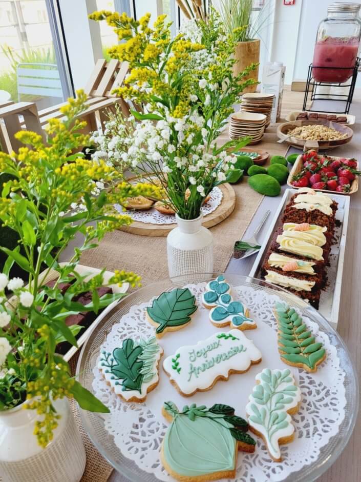 petit déjeuner healthy sur mesure par studio candy chez Hermès avec sablés décorés, carrot cake, fraises, granola, madeleines noisette, bouquets fleuris printaniers, fontaines à boissons de smoothie fraise et jus vert détox. Décoration nature, douce et fleurie.