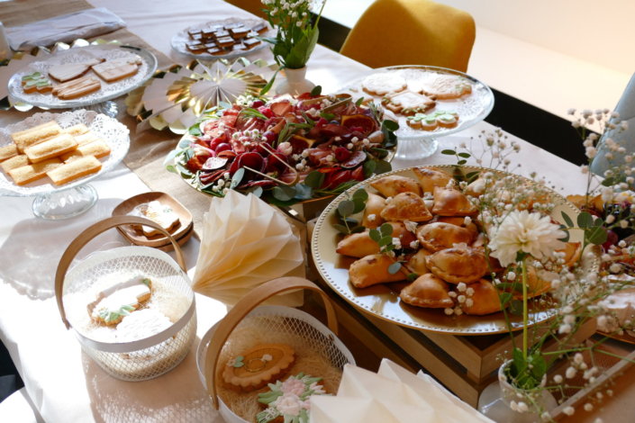 Jolie table thème mariage avec petites brochettes, salades, planche de fromages, feuilletés, sablés décorés wedding day, financiers, décoration or, blanc et petits bouquets de gypsophille