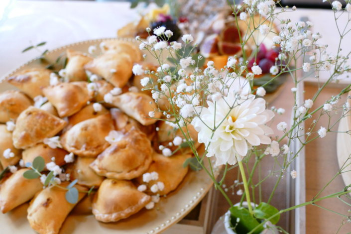 Jolie table thème mariage avec petites brochettes, salades, planche de fromages, feuilletés, sablés décorés wedding day, financiers, décoration or, blanc et petits bouquets de gypsophille