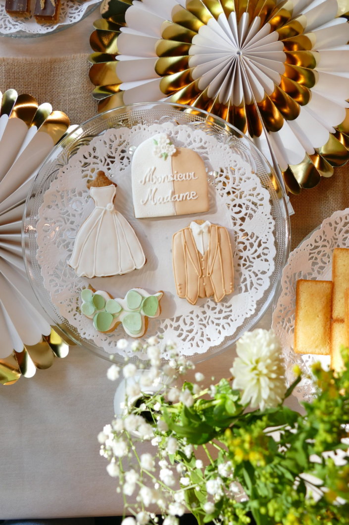 Jolie table thème mariage avec petites brochettes, salades, planche de fromages, feuilletés, sablés décorés wedding day, financiers, décoration or, blanc et petits bouquets de gypsophille